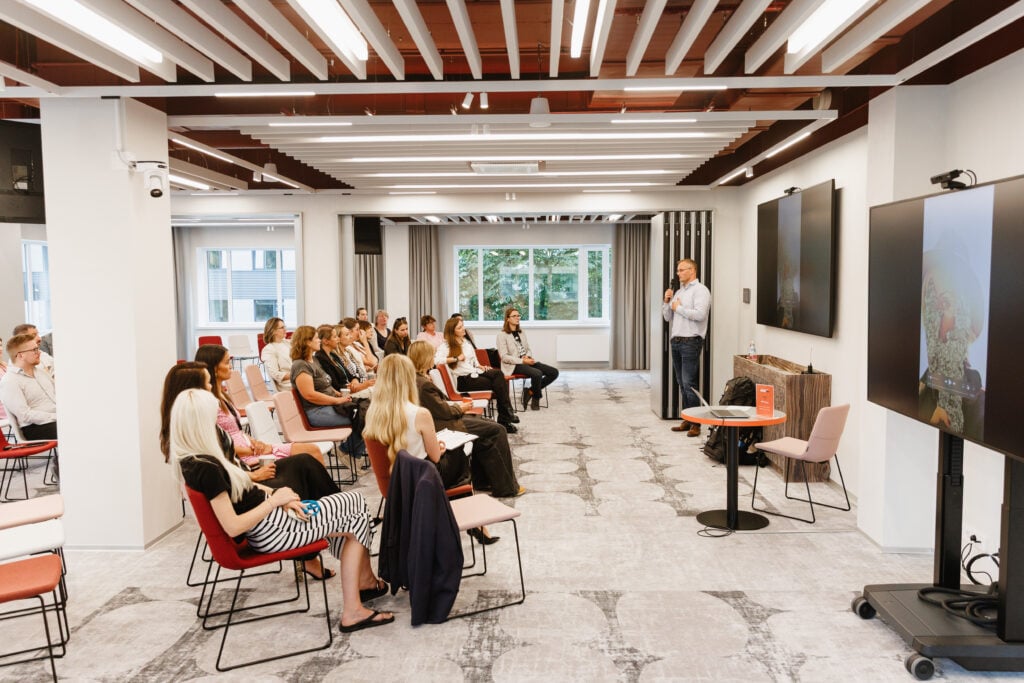 Person giving presentation to seated audience in conference room.