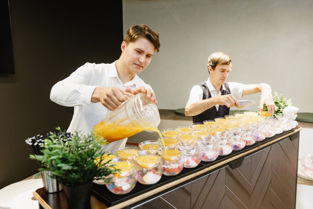 Two men preparing drinks at a bar setup.
