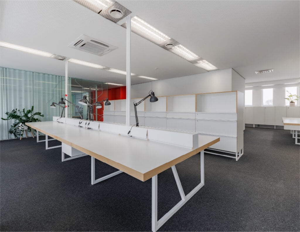 Modern open office with white desks and lamps.
