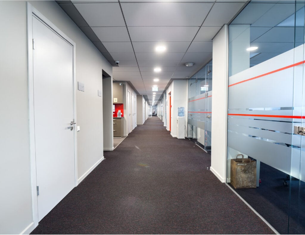 Modern office corridor with glass walls and doors.
