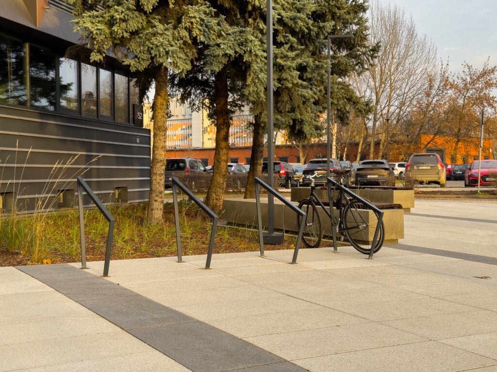 Railing and bicycles near modern office building.