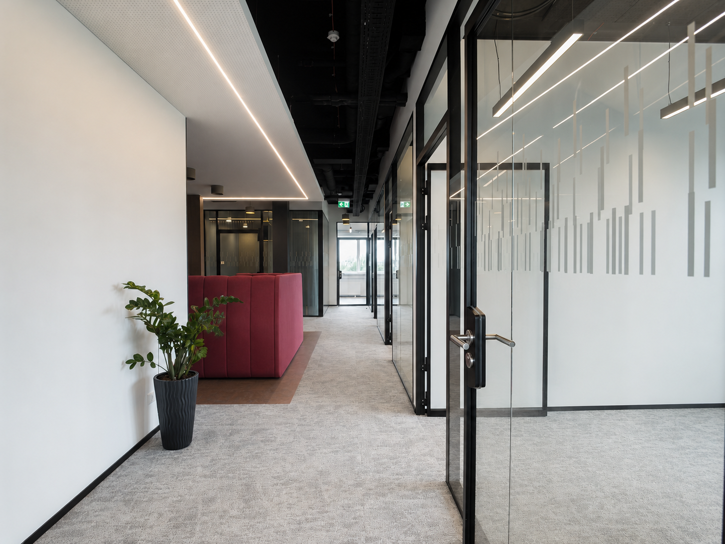 Modern office hallway with glass walls and red booth