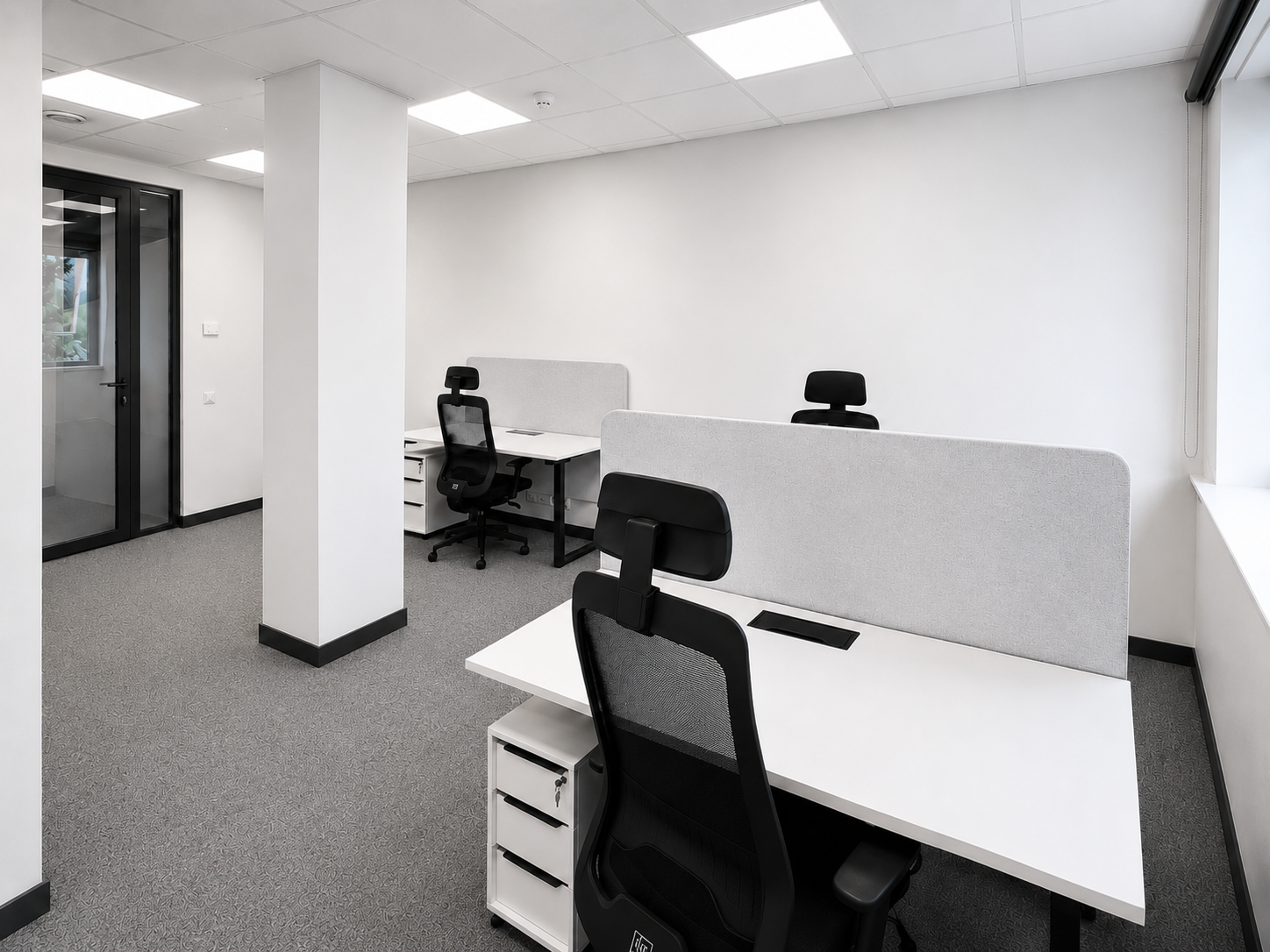Modern office workspace with desks, partitions, and ergonomic chairs